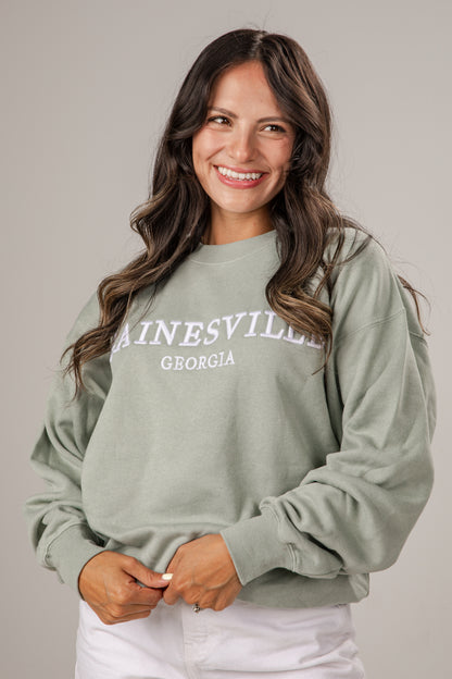 Woman wearing a light green sweatshirt with &