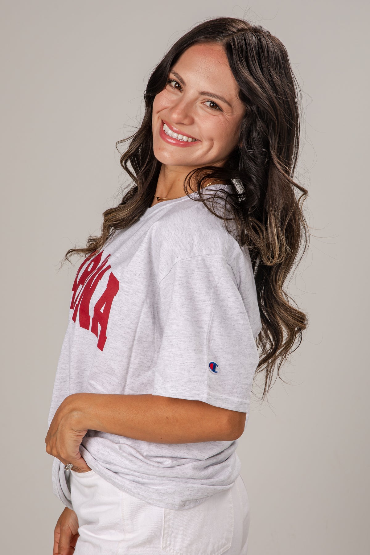 Woman wearing a gray t-shirt with red text on a plain background