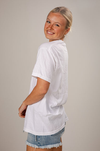 Woman wearing a white oversized shirt and denim shorts on a plain background