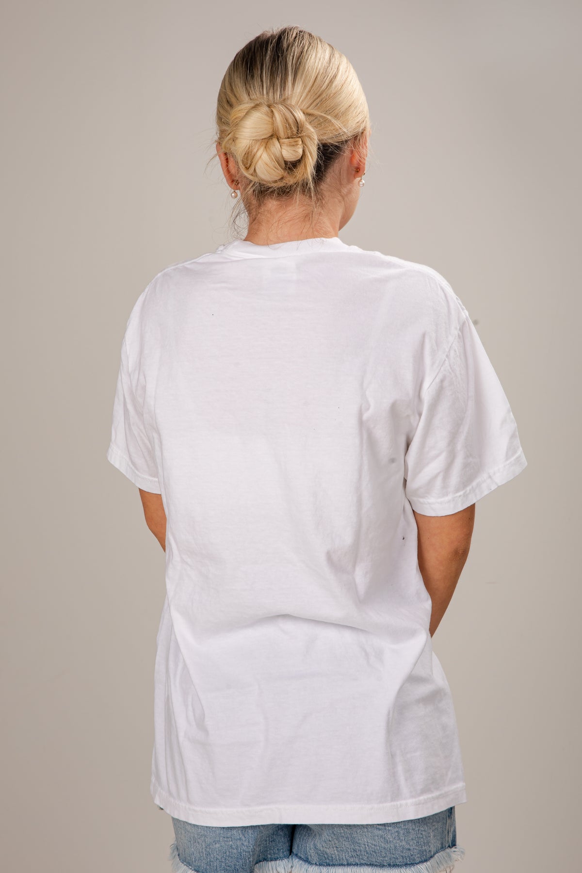 Person wearing a plain white t-shirt against a neutral background