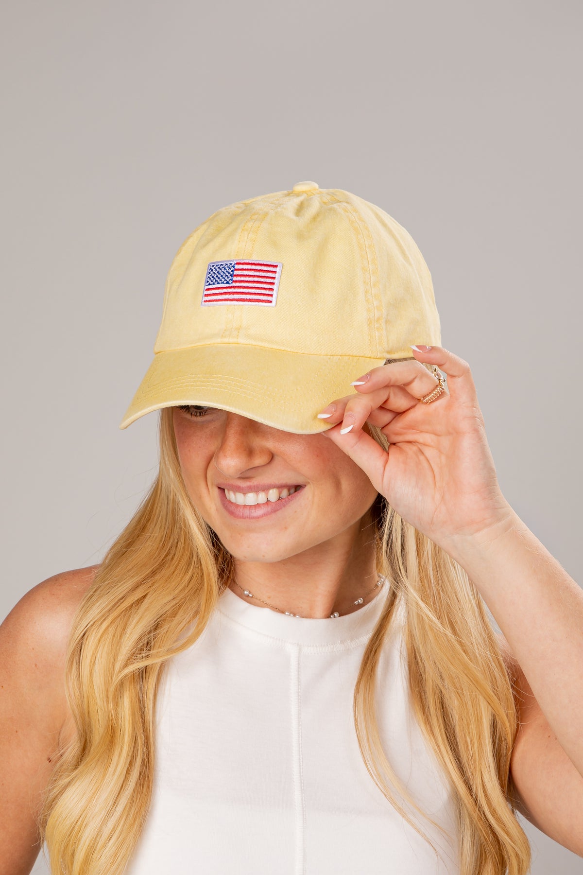 Person wearing a yellow cap with an American flag patch on a gray background