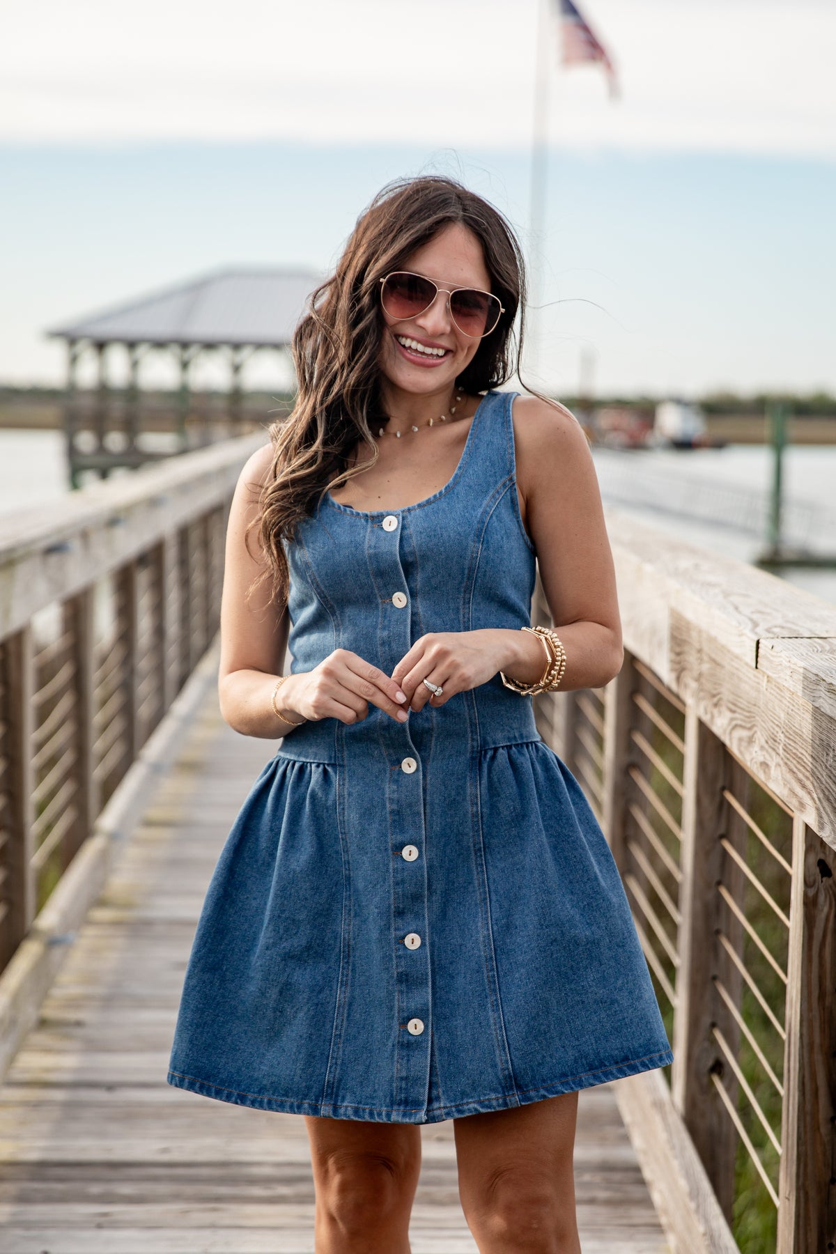 Woman wearing a blue denim dress on a wooden dock.