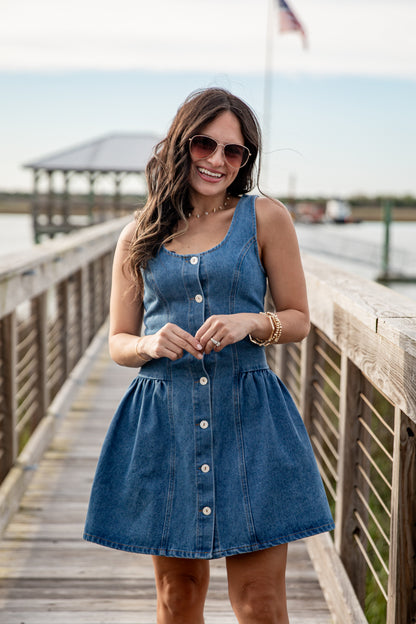 Woman wearing a blue denim dress on a wooden dock.