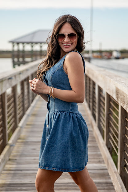 Woman wearing a blue denim dress on a wooden pier.