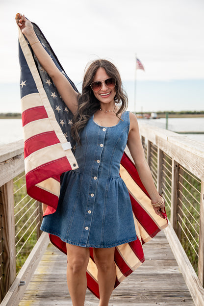 Woman holding an American flag on a wooden dock with a scenic background