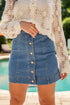 Person wearing a beige lace top and blue denim skirt by a pool.