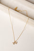 Gold necklace with a bow pendant on a light beige surface