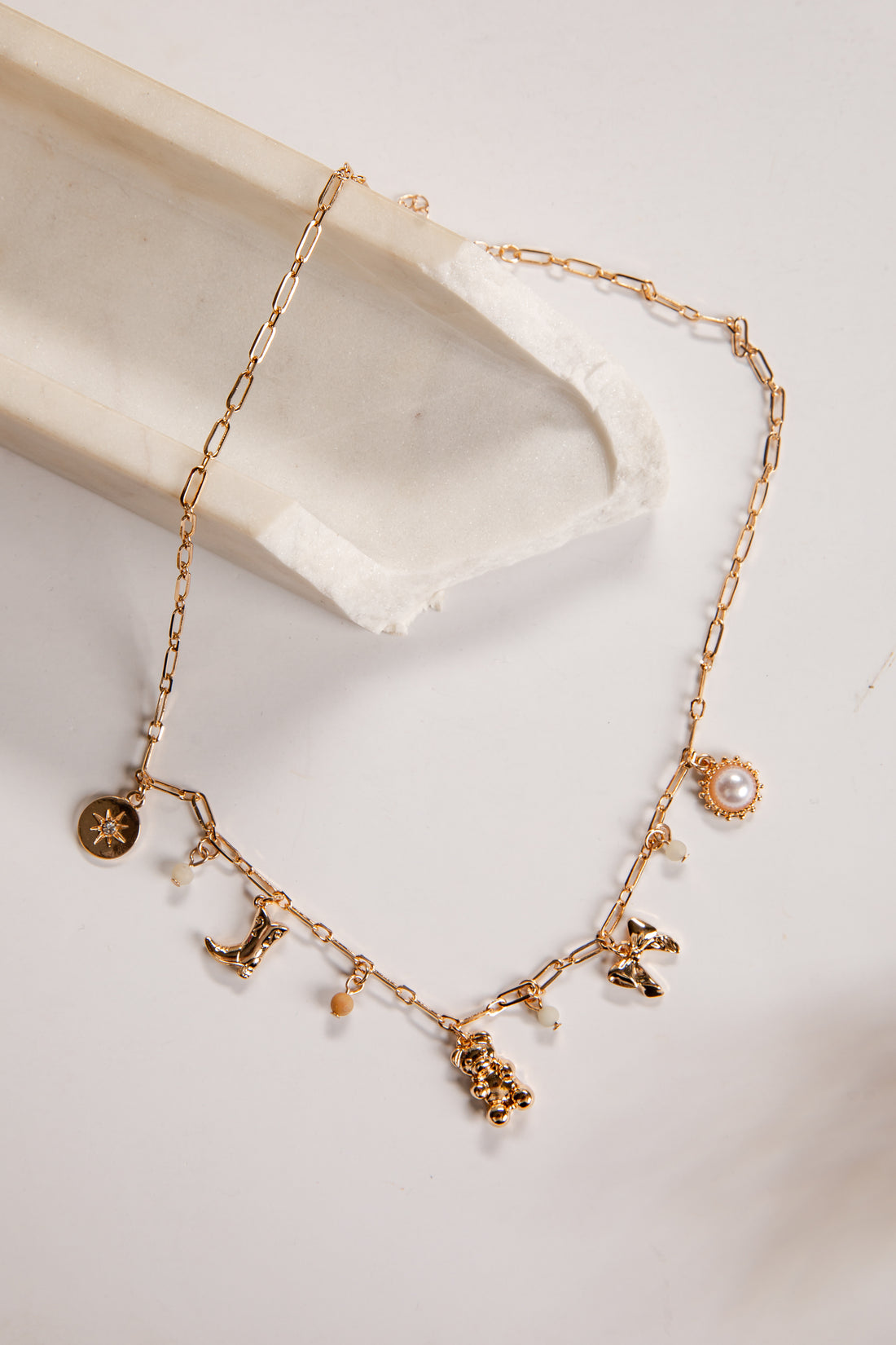 Gold necklace with charms on a white dish