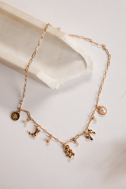 Gold necklace with charms on a white dish
