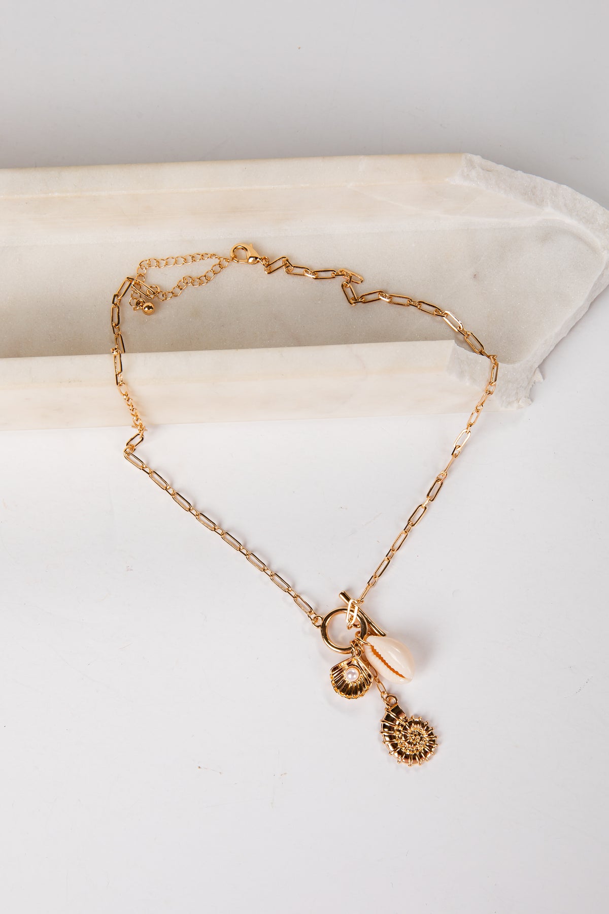 Gold necklace with charms on a white surface