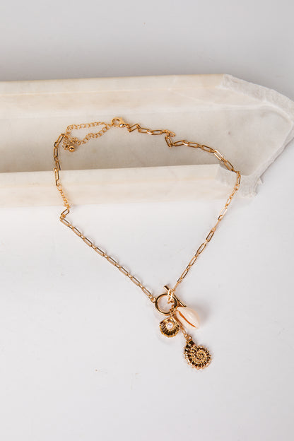 Gold necklace with charms on a white surface