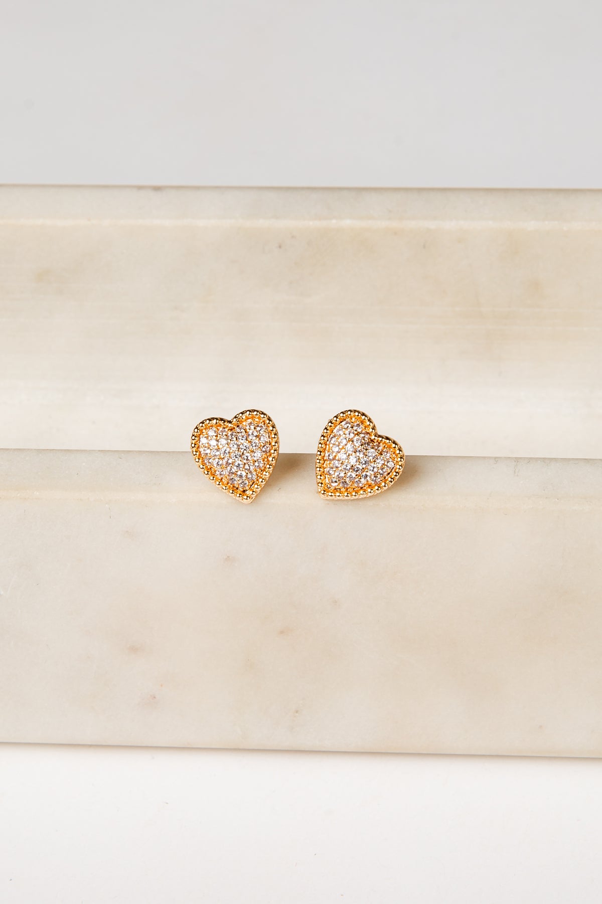 Heart-shaped gold earrings on a marble surface