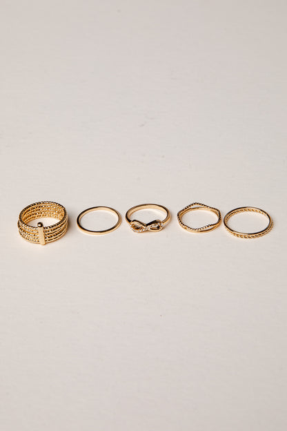 Set of five gold rings on a light gray background