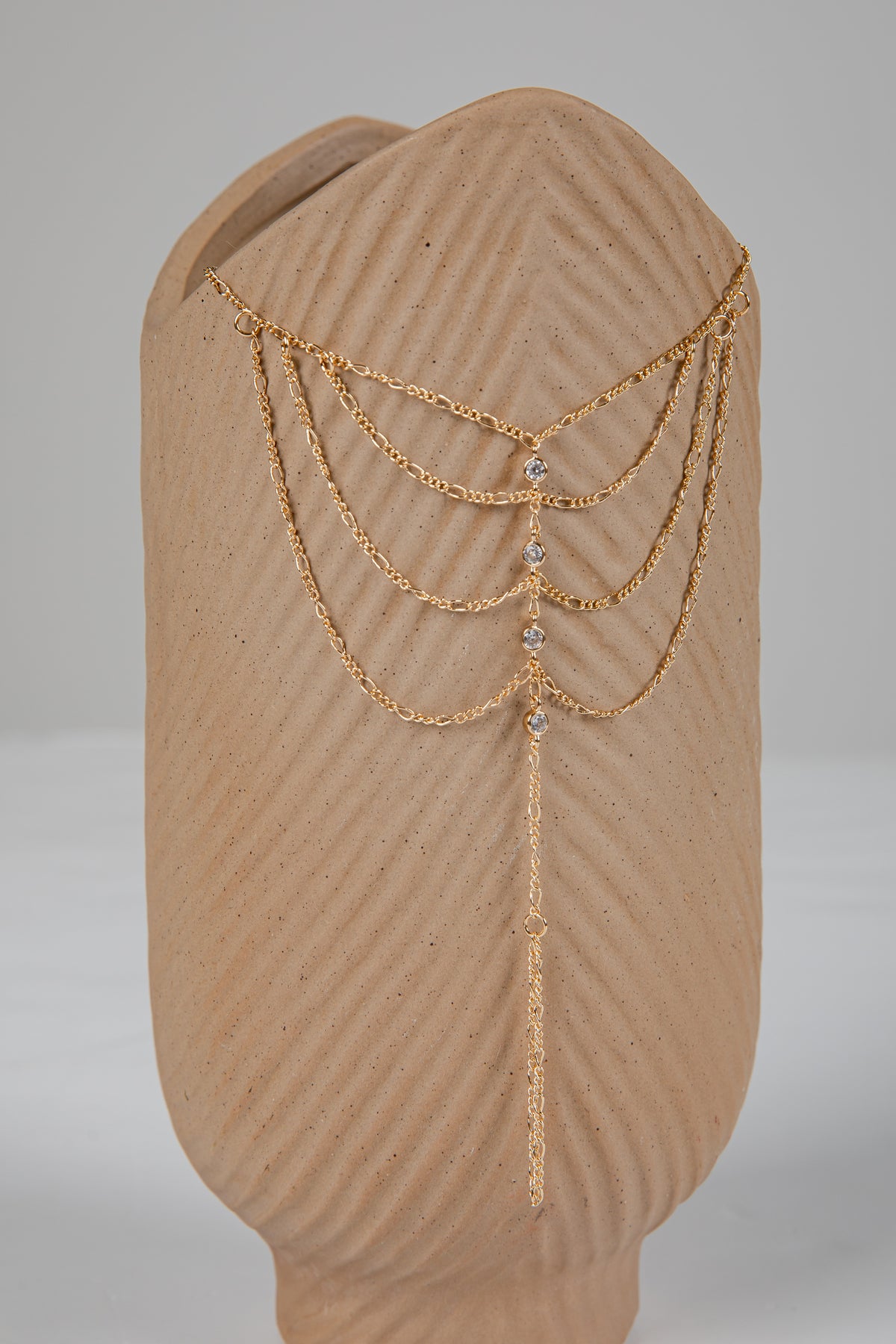 Gold chain headpiece on a mannequin head with a plain background
