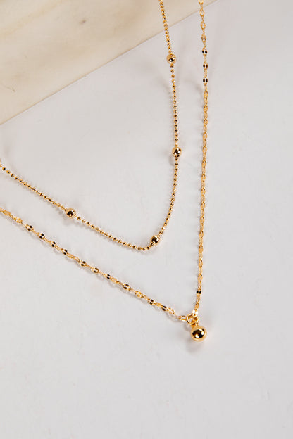 Gold necklace on a light gray surface