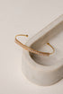 Gold bracelet with clear stones on a marble surface