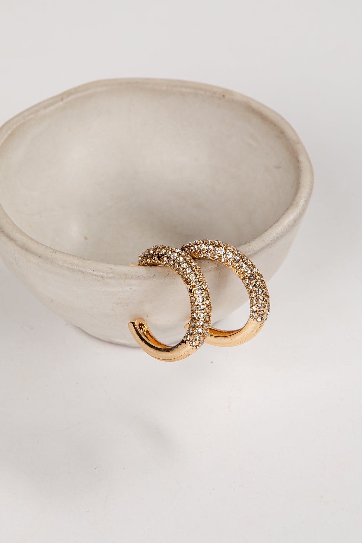 Gold crescent moon-shaped earrings on a white dish