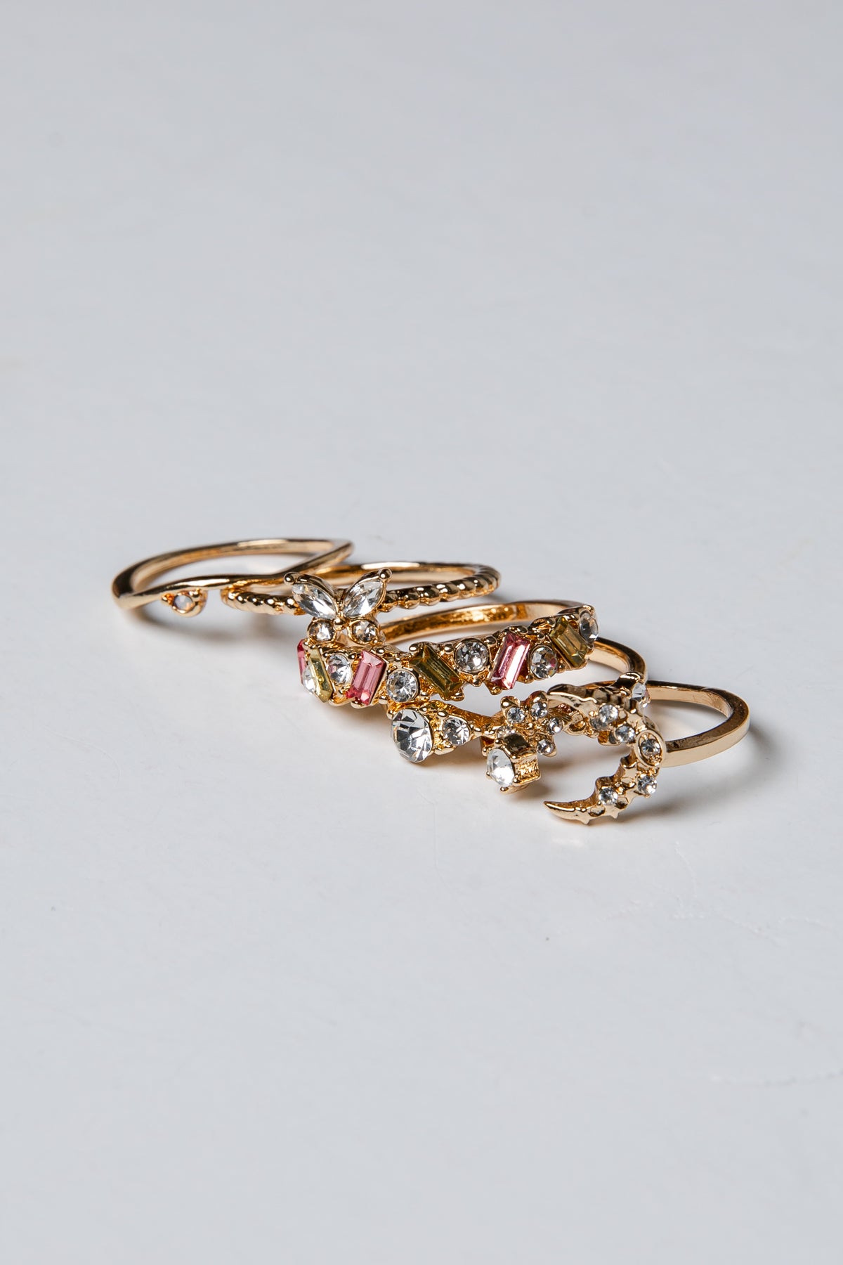 Gold rings with gemstones on a light gray background