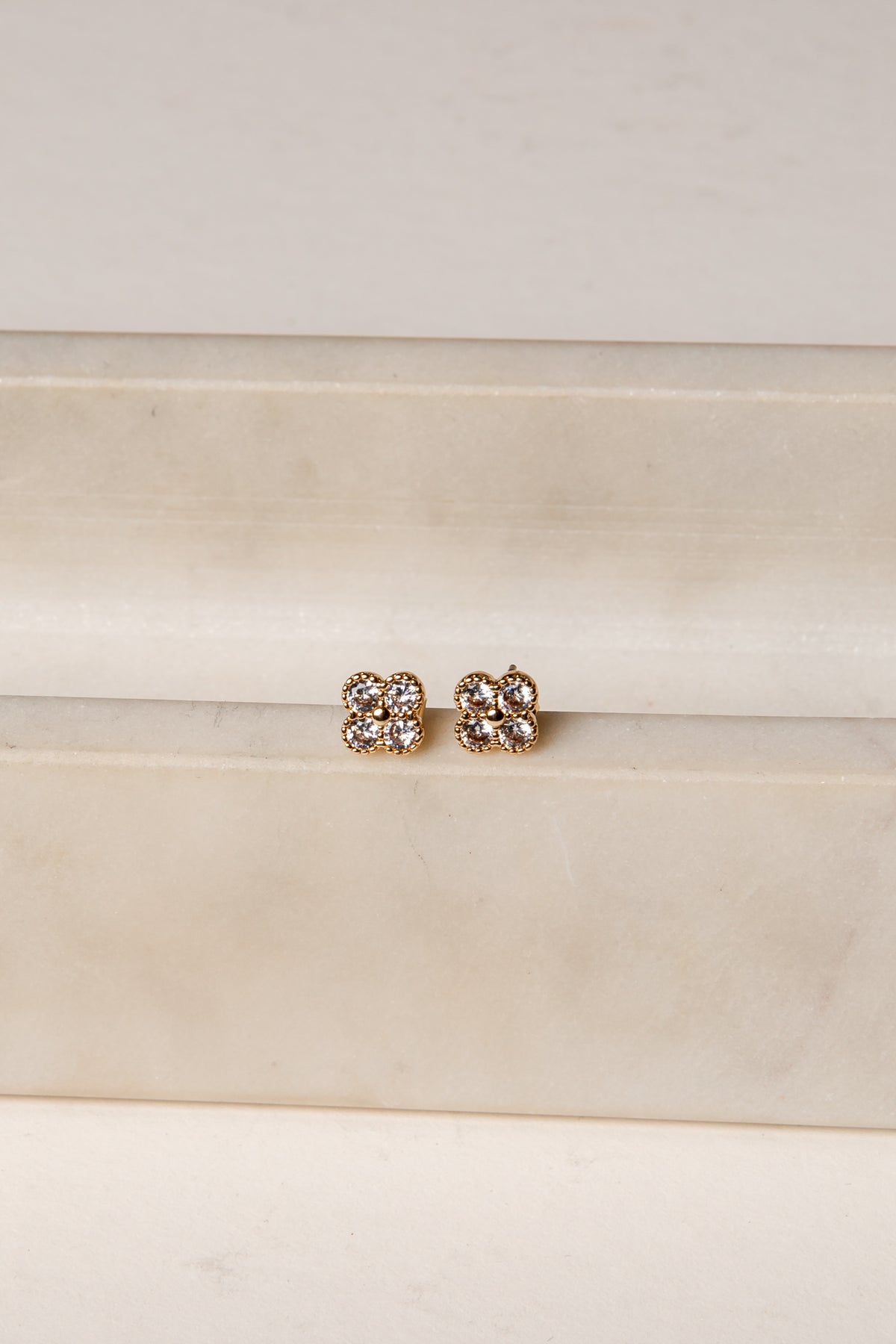 Pair of gold earrings with clear stones on a white background