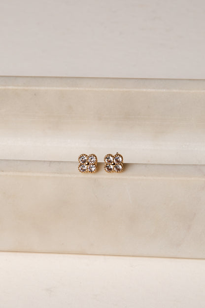 Pair of gold earrings with clear stones on a white background