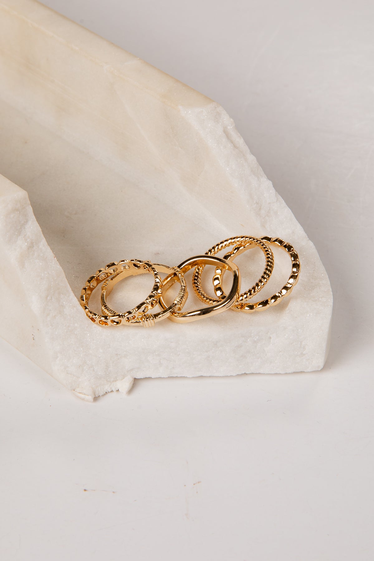 Three gold rings stacked on a white stone surface