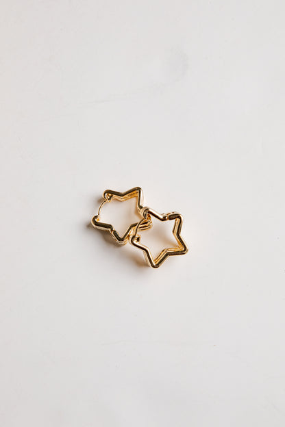 Gold star-shaped earrings on a light gray background
