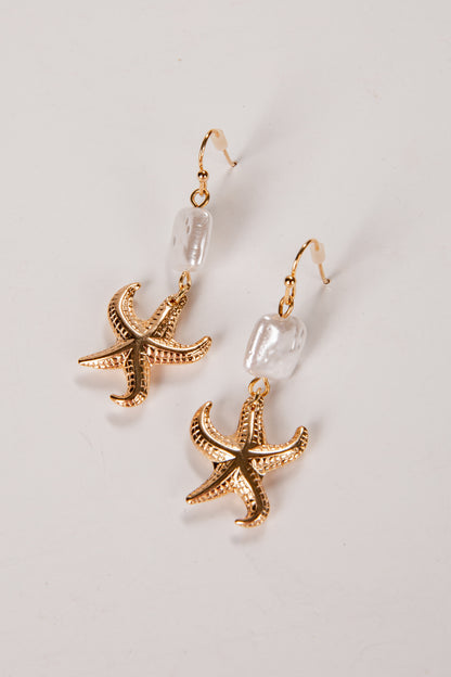 Gold starfish earrings on a light gray background