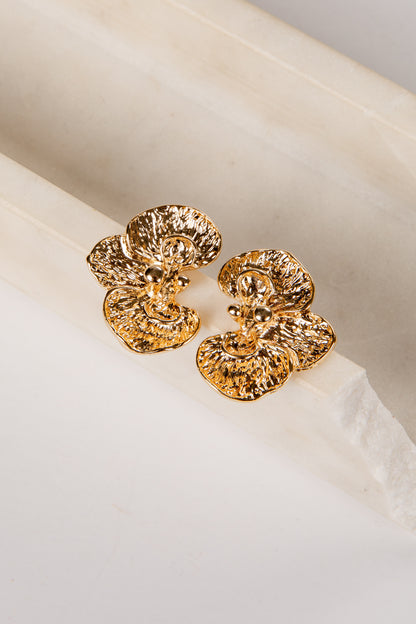 Gold earrings on a white fabric background