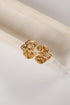 Gold floral earrings on a white fabric background