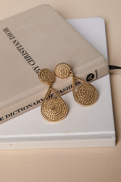 Gold earrings on a book with a beige cover