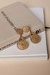 Gold earrings on a book with a beige cover