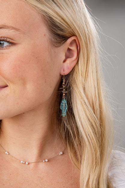 Close-up of a woman wearing turquoise earrings with a neutral background