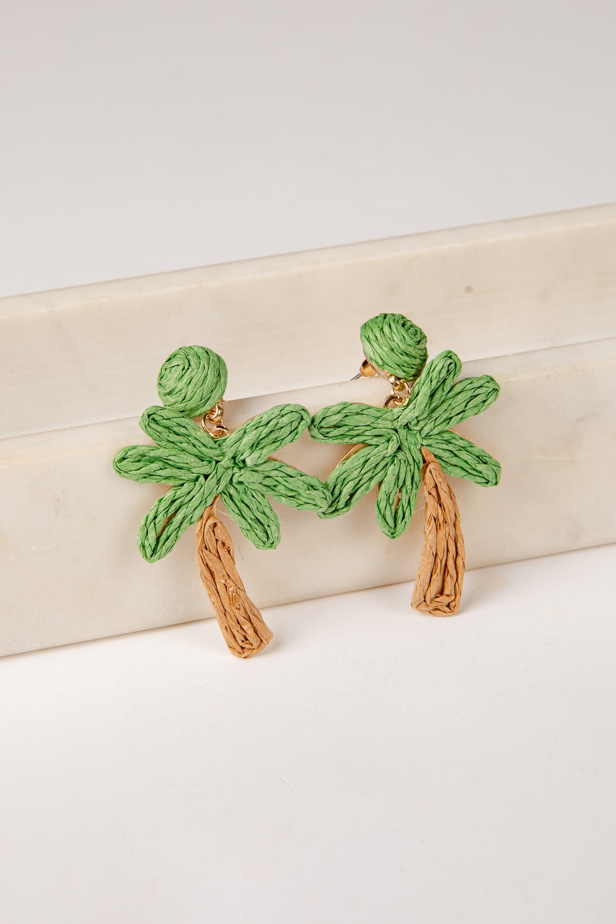 Palm tree earrings on a light wooden surface