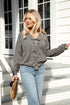 Woman wearing a gray sweater and blue jeans standing on wooden steps.