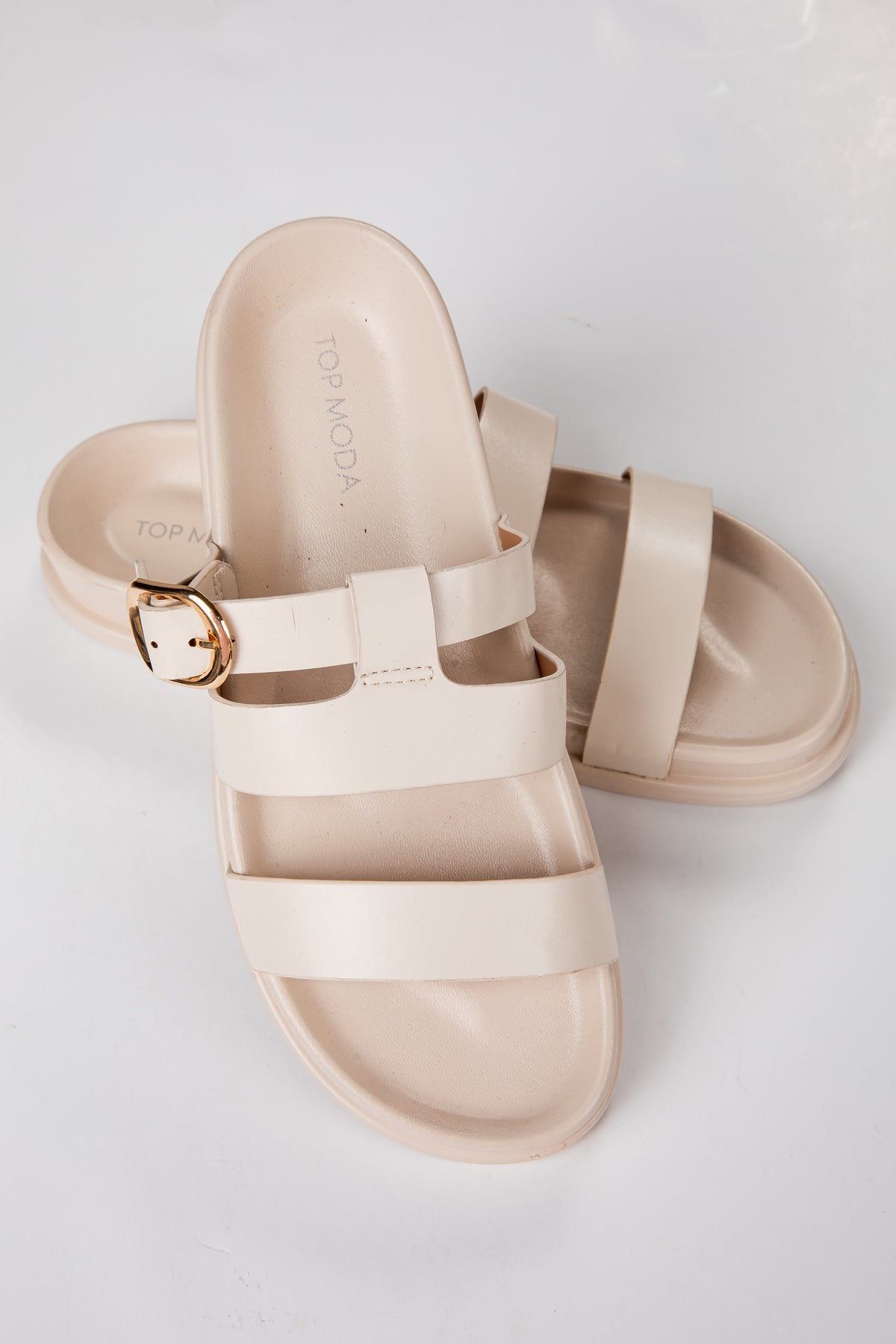 Beige sandals with a buckle on a light gray background
