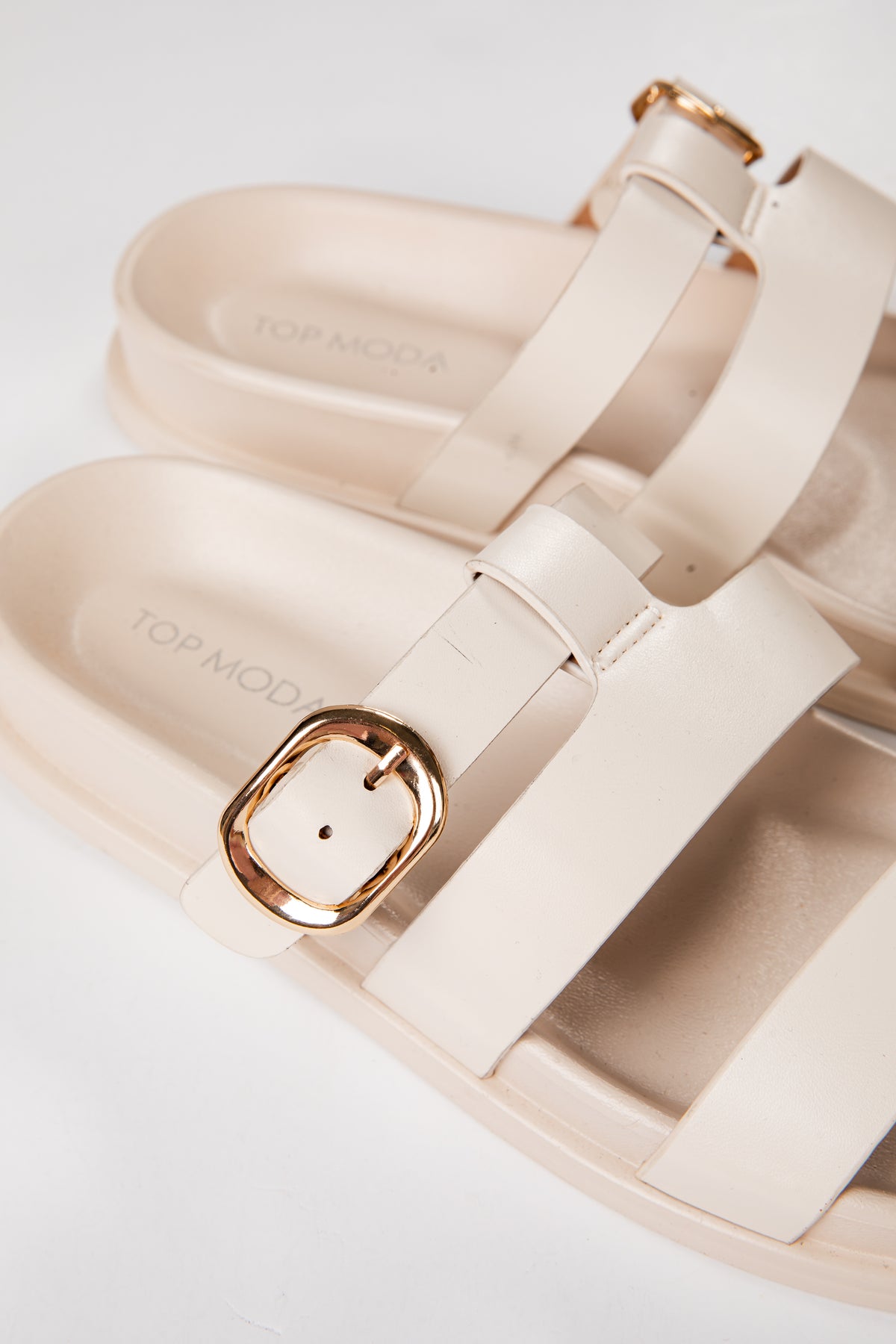 Beige sandals with gold buckles on a light background
