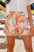 Person wearing colorful leaf-patterned shorts with a blurred outdoor background