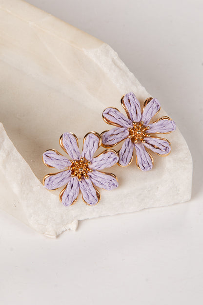 Purple flower earrings on a white fabric background