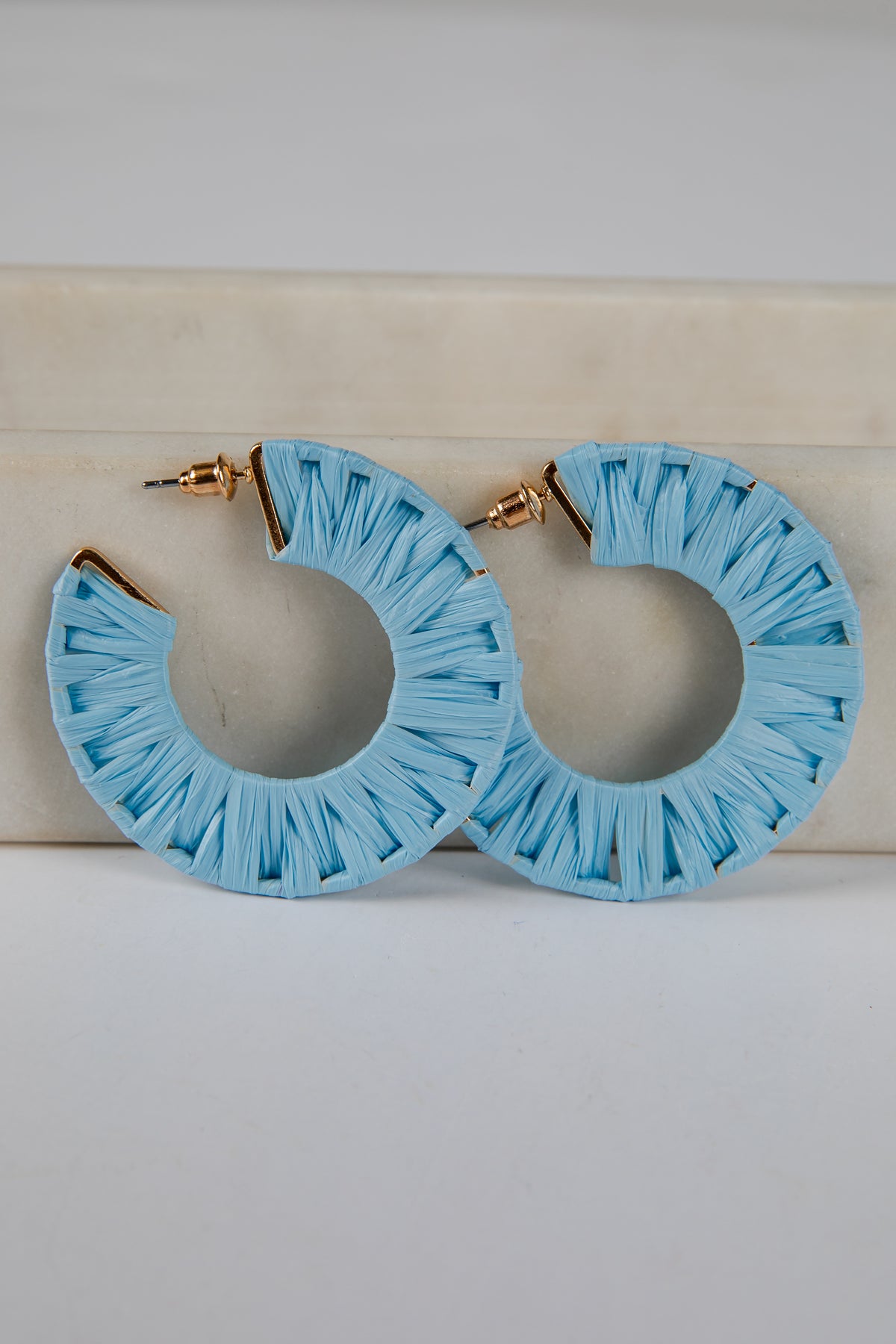 Light blue hoop earrings with ruffled edges on a light background