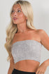 Woman wearing a strapless gray top against a plain background