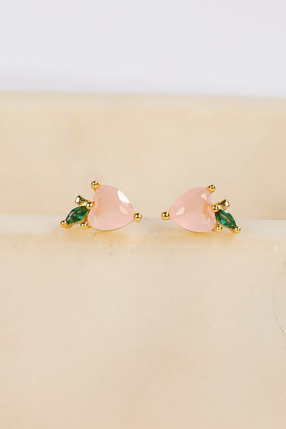 Pair of earrings with pink and green stones on a beige background