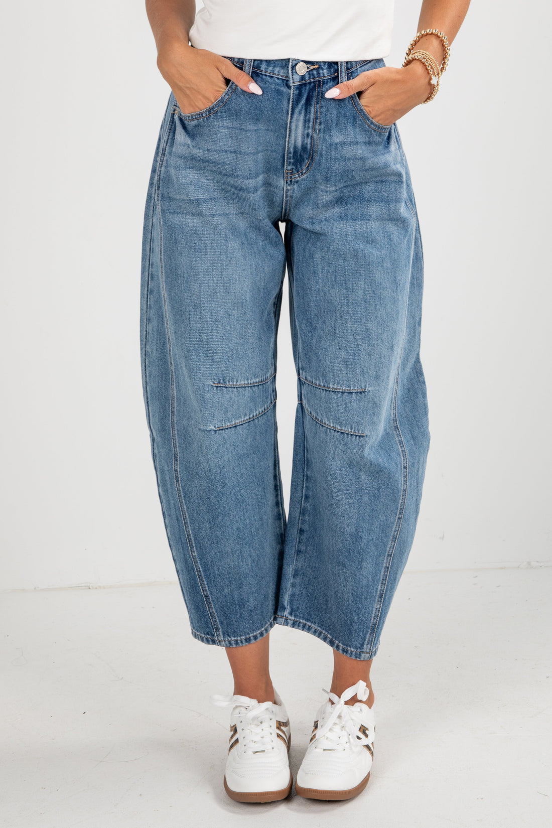 Person wearing blue jeans and white sneakers on a plain background