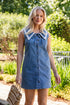 Model wearing a medium wash denim button-front mini dress with a lace-trim collar, front tie detail, and sleeveless design.