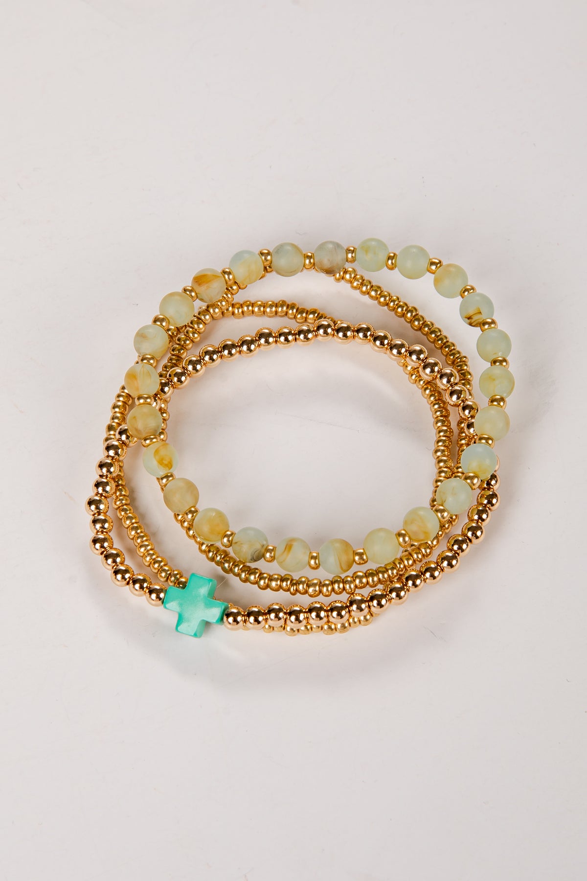 Set of gold and green beaded bracelets on a light background