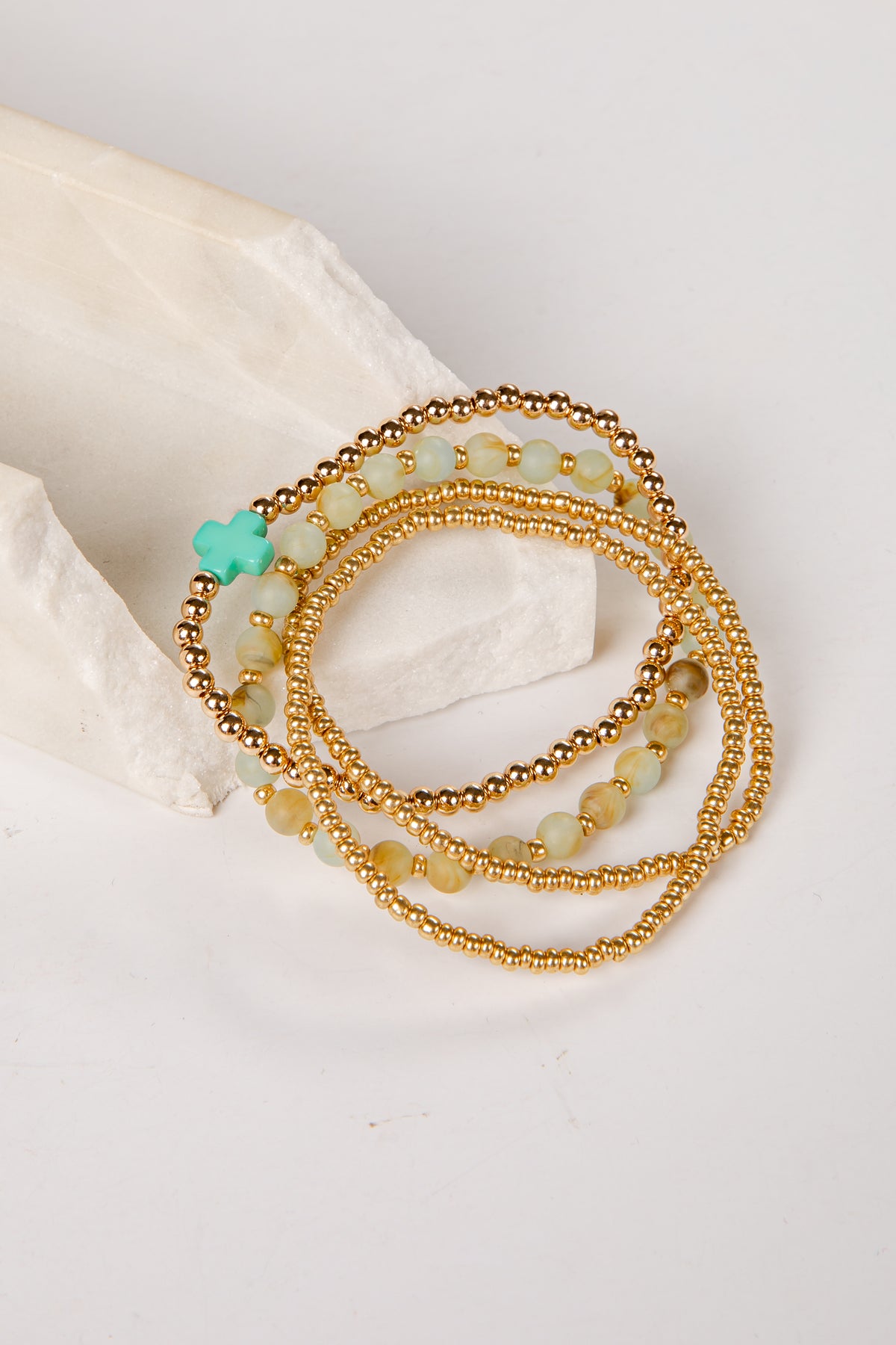 Set of gold and green beaded bracelets on a light background
