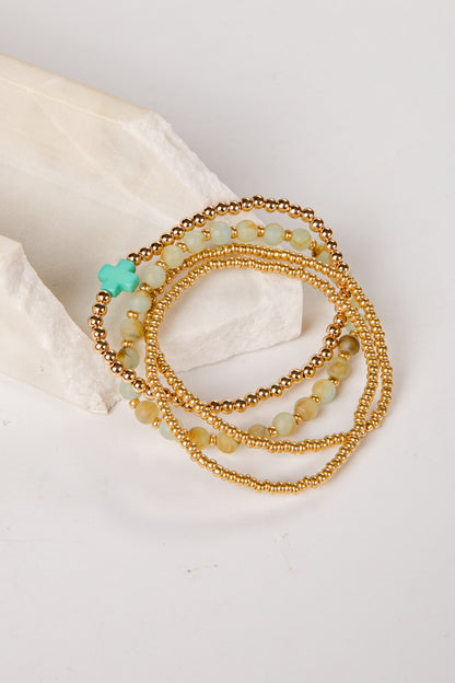 Set of gold and green beaded bracelets on a light background