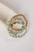 three bracelets with green beads and gold accents on a light gray background