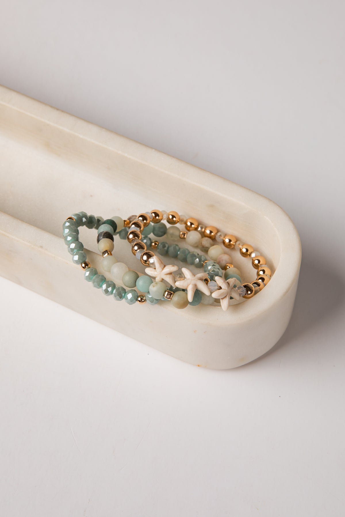 Set of beaded bracelets with starfish charm on a white dish