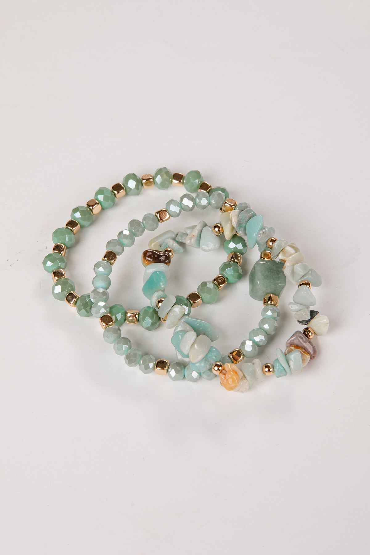 Beaded bracelets with green and gold beads on a light gray background