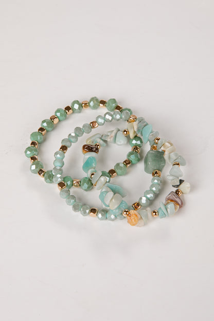 Beaded bracelets with green and gold beads on a light gray background